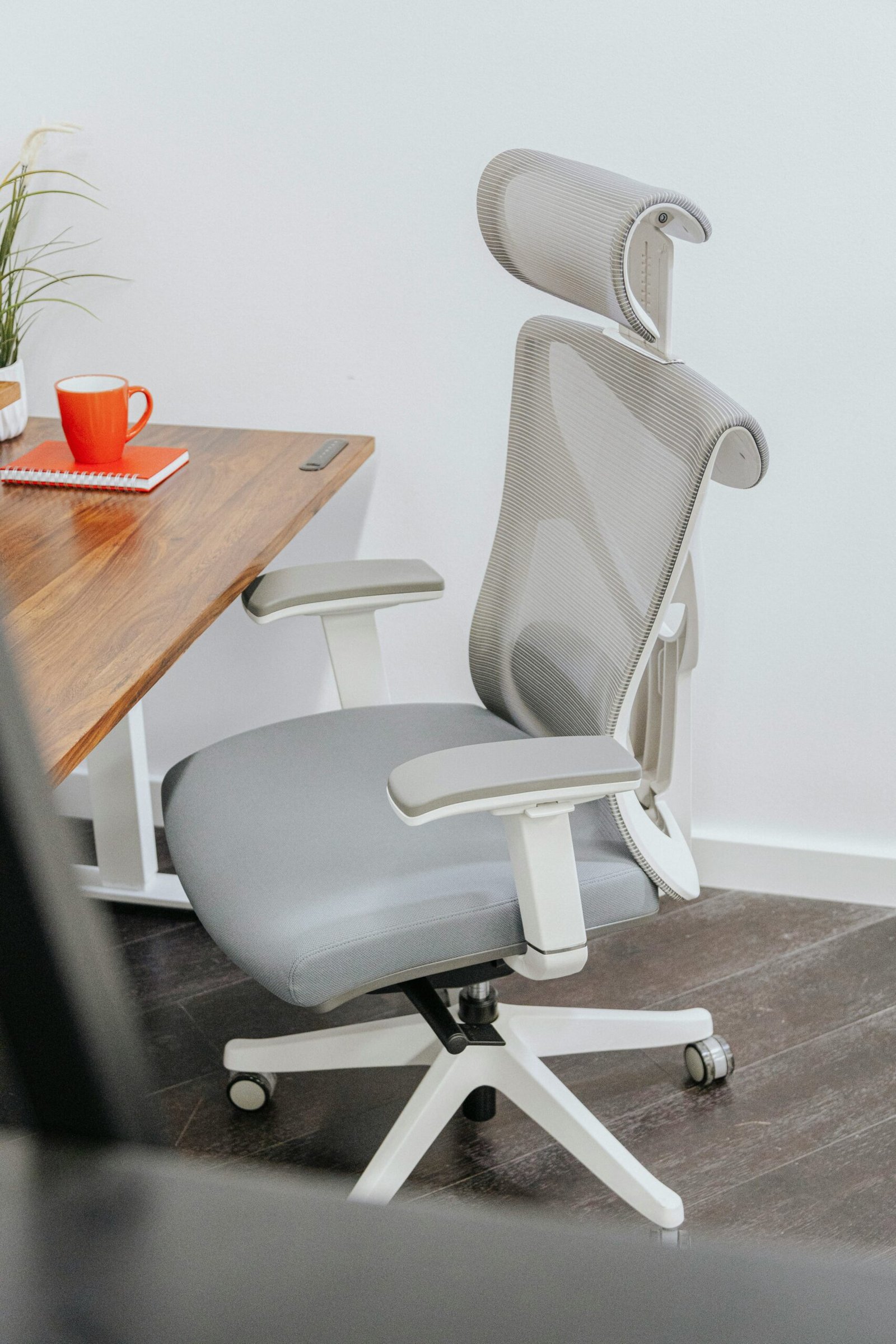 Silla de oficina ergonómica gris junto a escritorio de madera